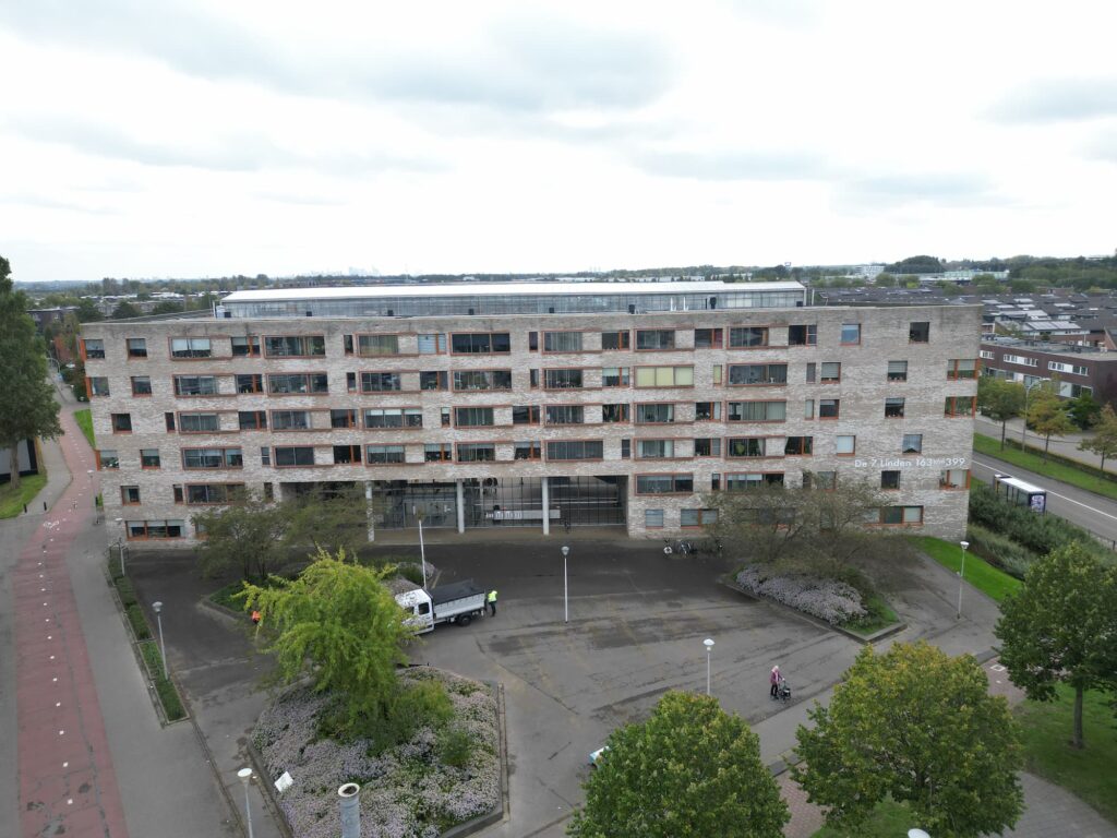 Voorgevel van een modern appartementencomplex aan de Z. Linden 143/WH299 met een groene voortuin en een oprit.