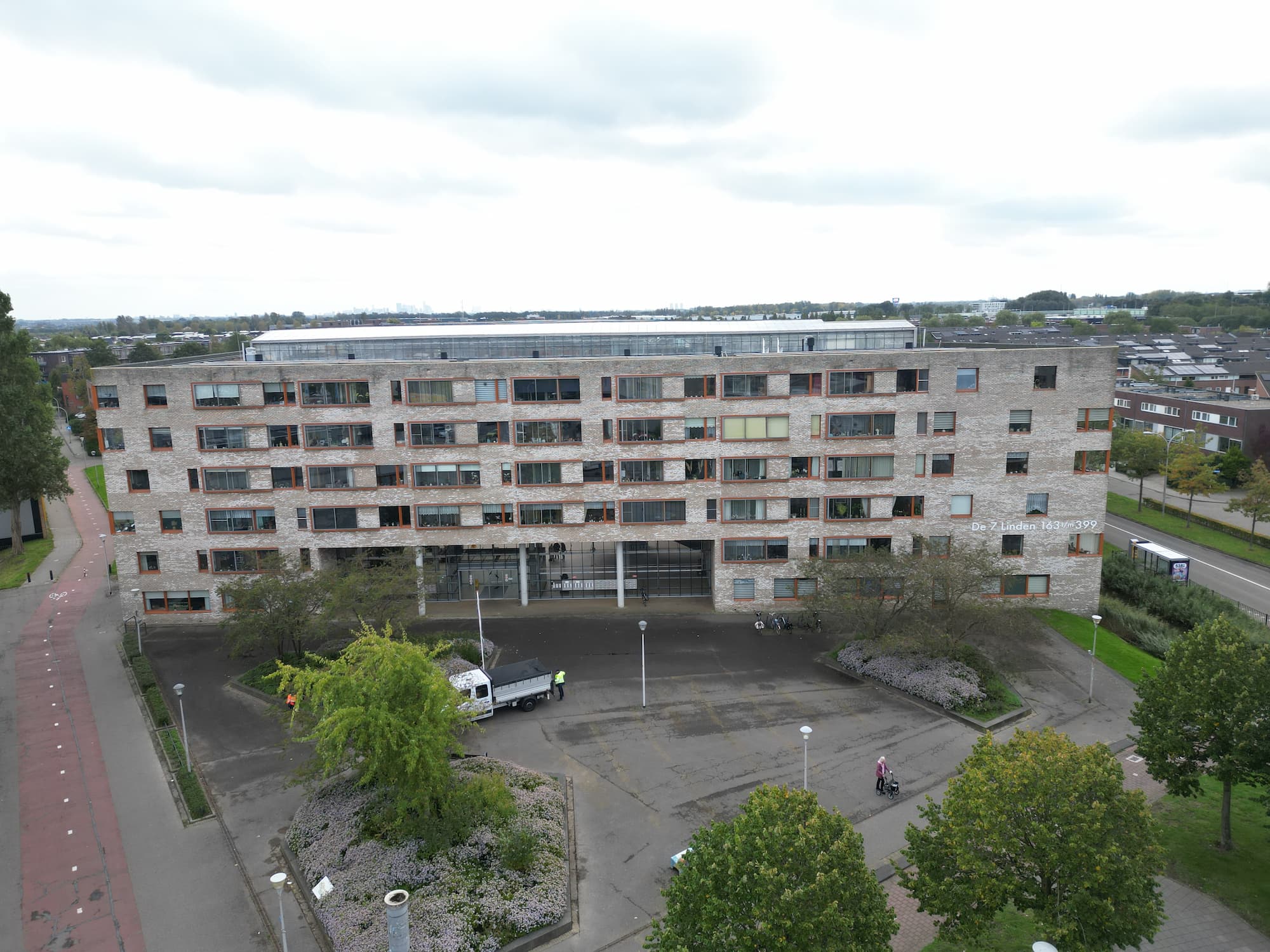 Voorgevel van een modern appartementencomplex aan de Z. Linden 143/WH299 met een groene voortuin en een oprit.
