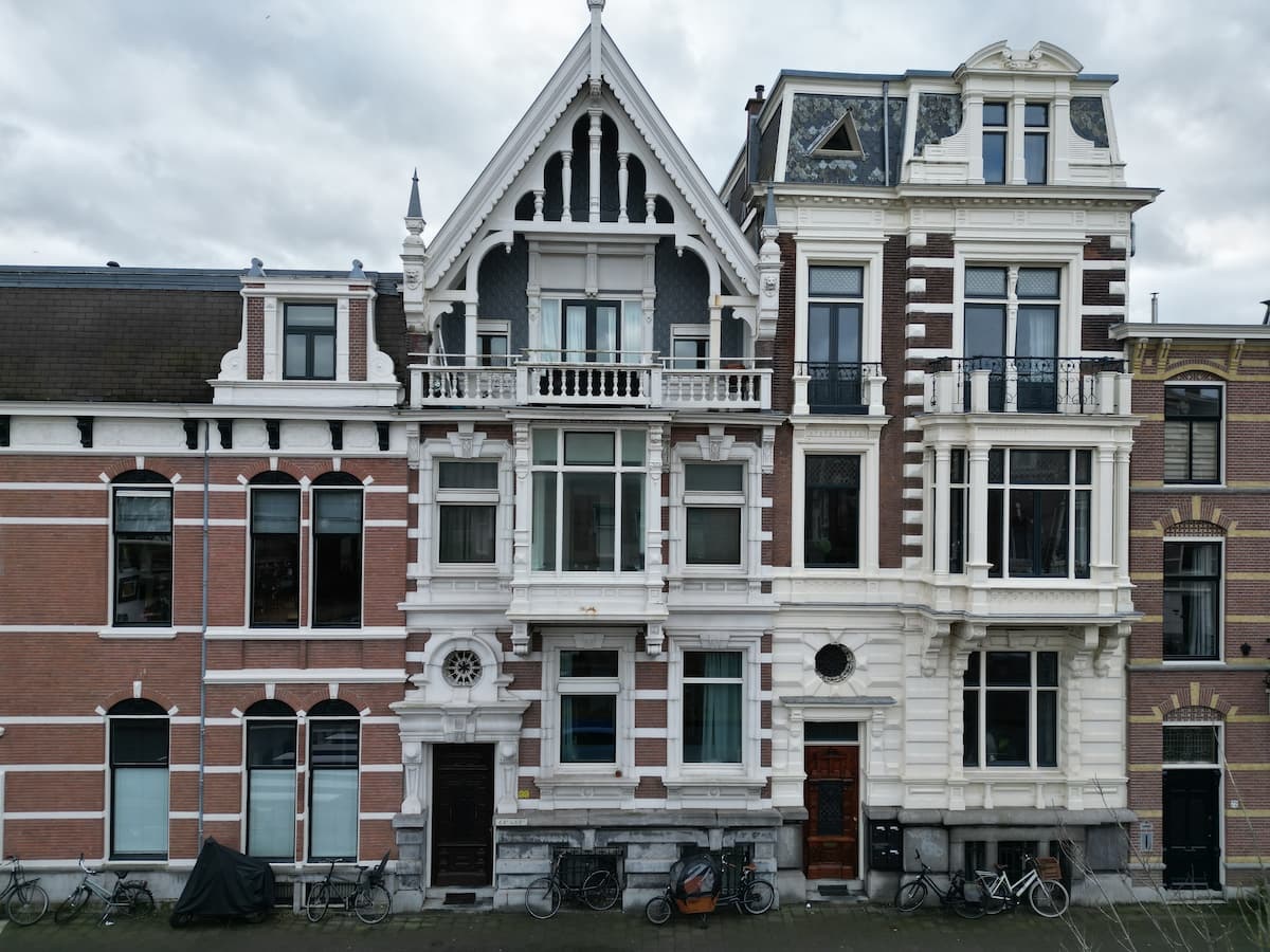 Voorgevel van een historisch pand met rijke architectonische details en fietsen geparkeerd op de stoep.